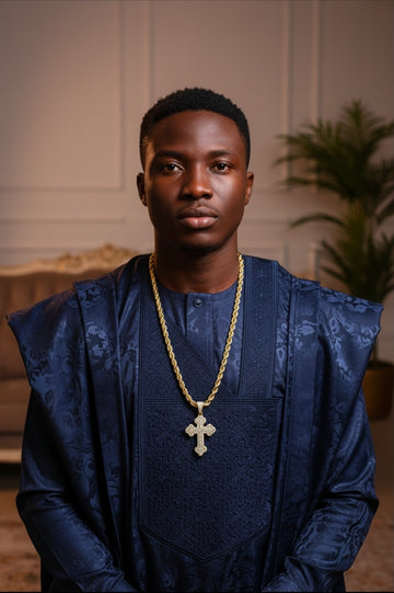 Gold plated iced out cross pendant necklace worn by a male model in blue traditional agbada - Fancydaria