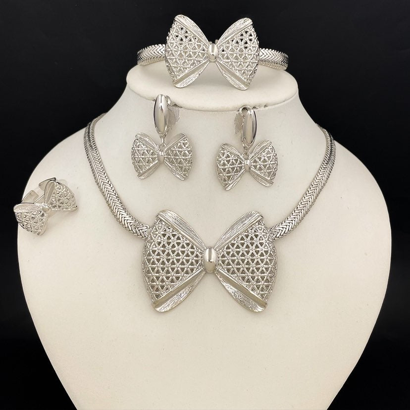 Silver bow-shaped jewelry set on a mannequin bust against a black background