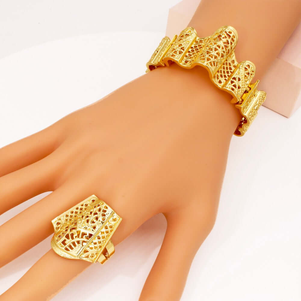 Gold bracelet and ring on a hand against a white background