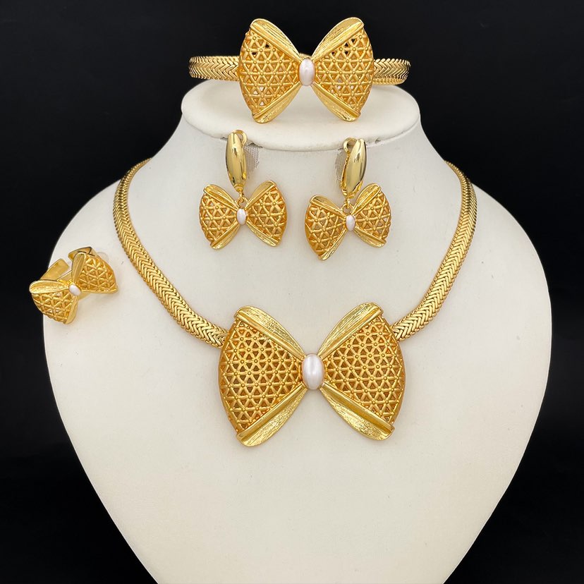 Gold jewelry set including necklace, earrings, and bracelet on a white stand with a black background.