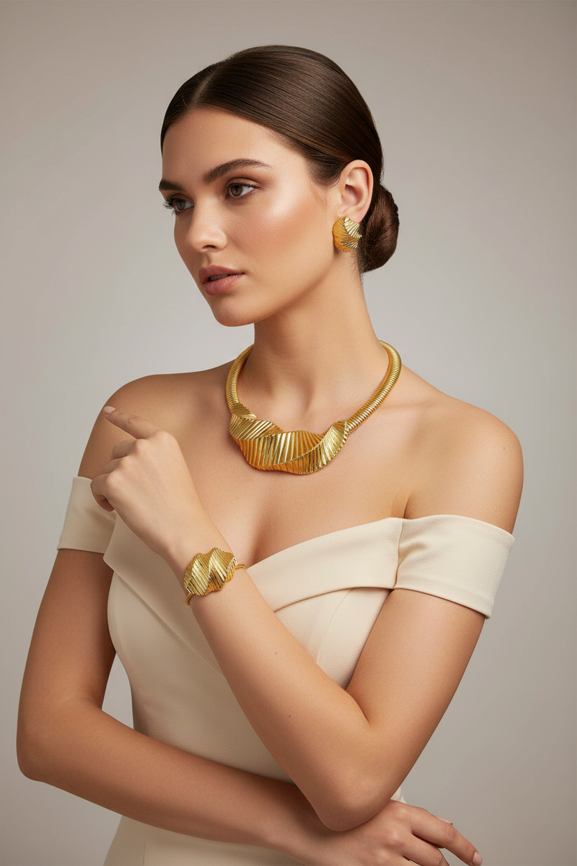 Woman wearing gold jewelry including a necklace, earrings, and bracelet against a neutral background
