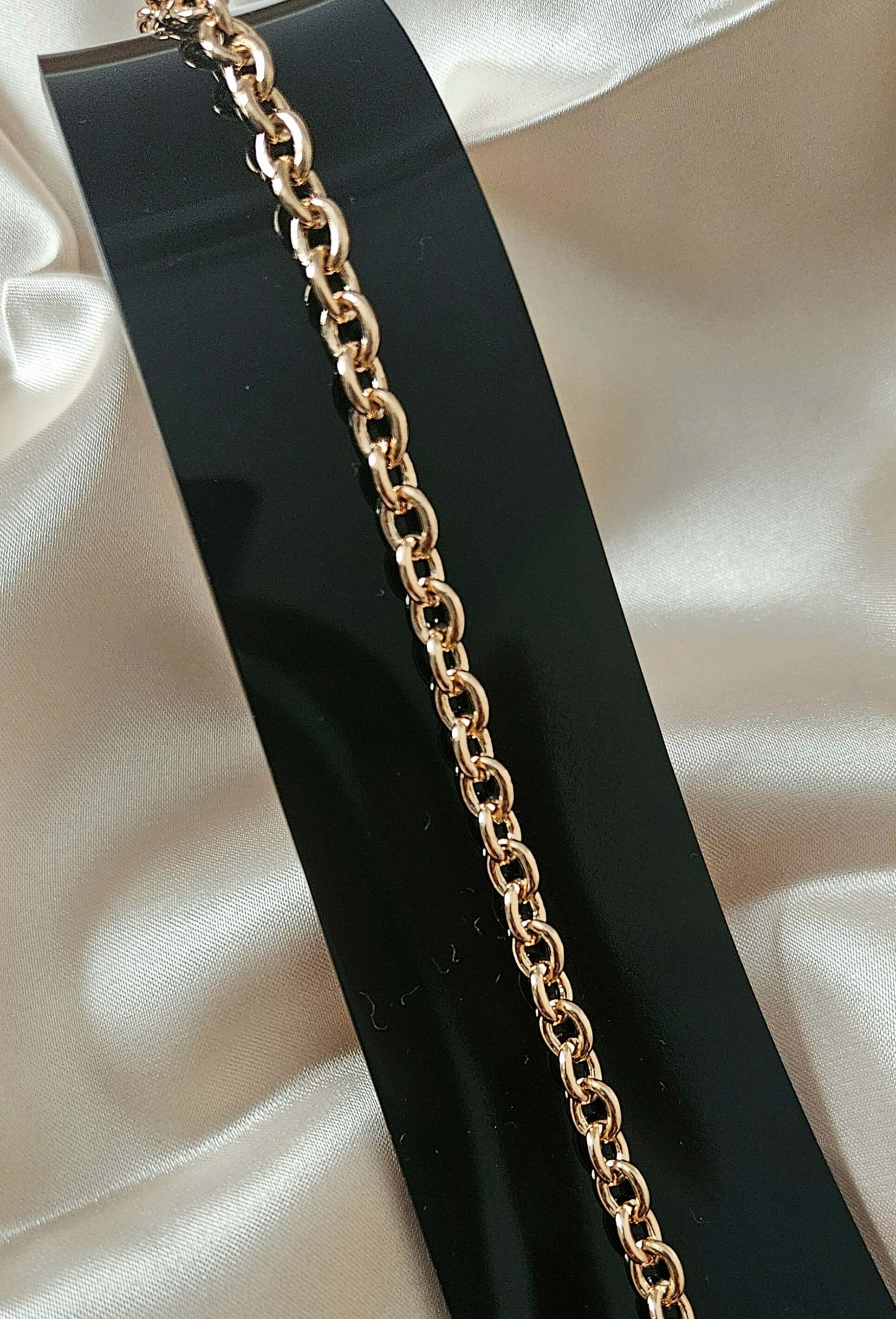 Gold chain on a black stand with a white fabric background