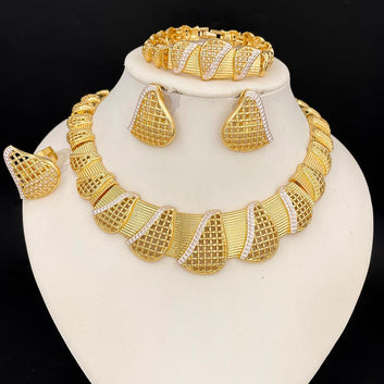 Gold jewelry set including necklace, earrings, and bracelet on a white stand with a black background.
