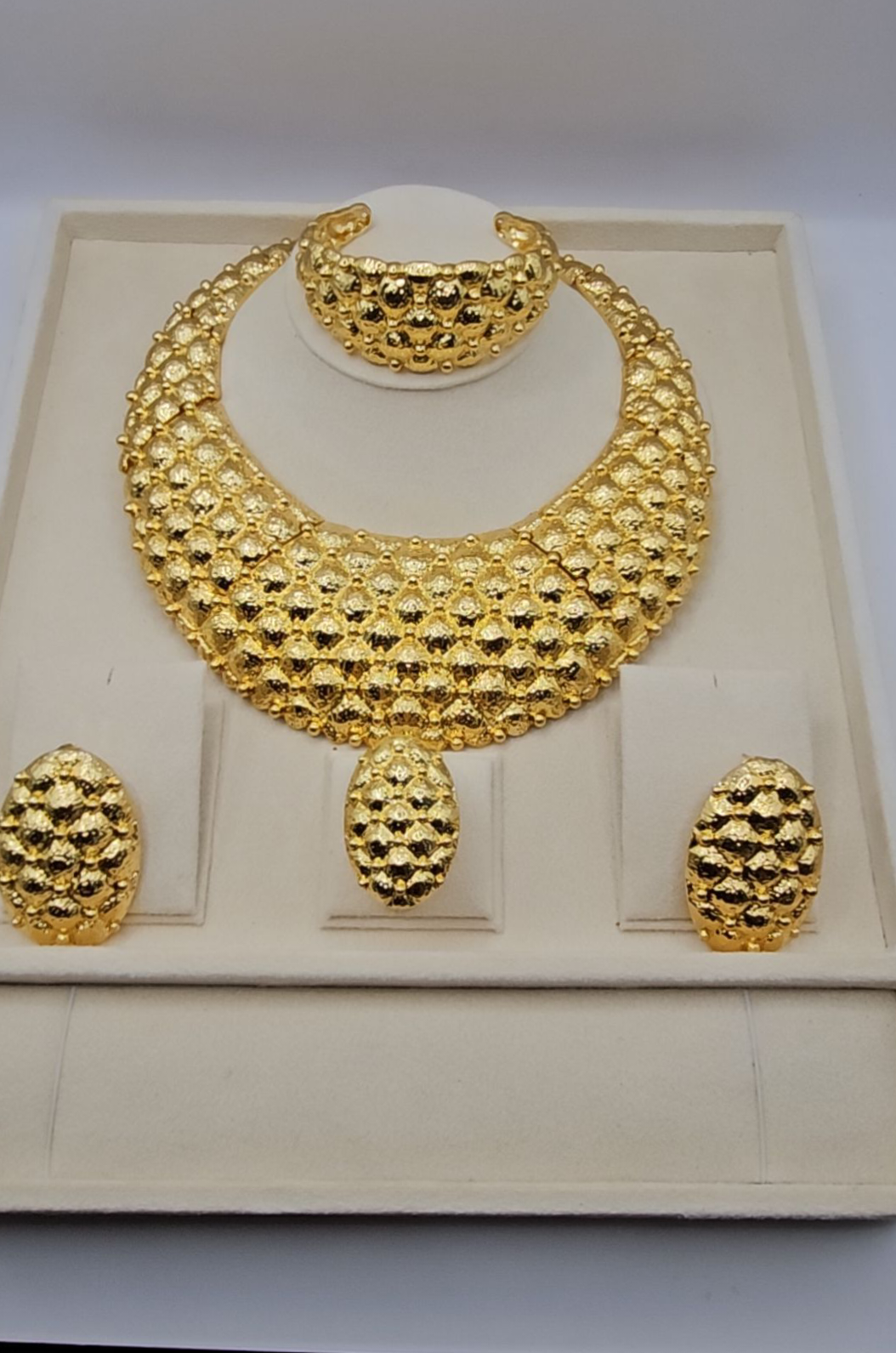 Gold necklace and earrings set on a white box