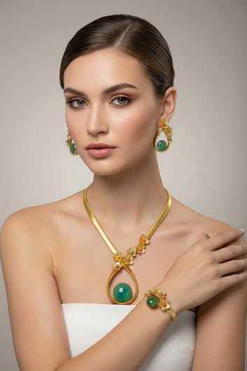 Gold and green jewelry set on a black mannequin bust with a white background