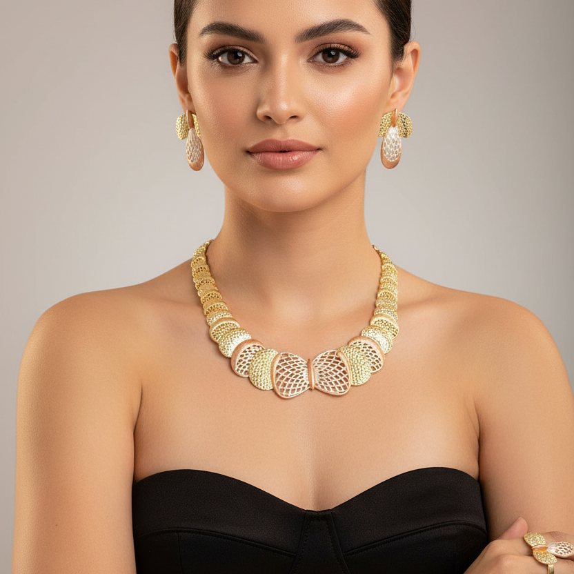 Woman wearing gold jewelry including a necklace, earrings, and bracelet against a neutral background