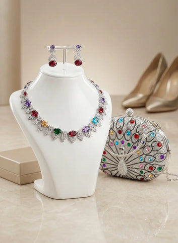 Jewelry set with necklace, earrings, and clutch on a white stand with high heels in the background.