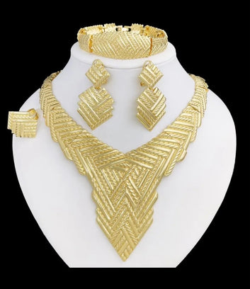 Gold jewelry set including necklace, earrings, and bracelet on a white stand.
