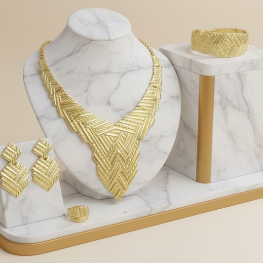 Gold jewelry set including necklace, earrings, and bracelet on a marble stand.