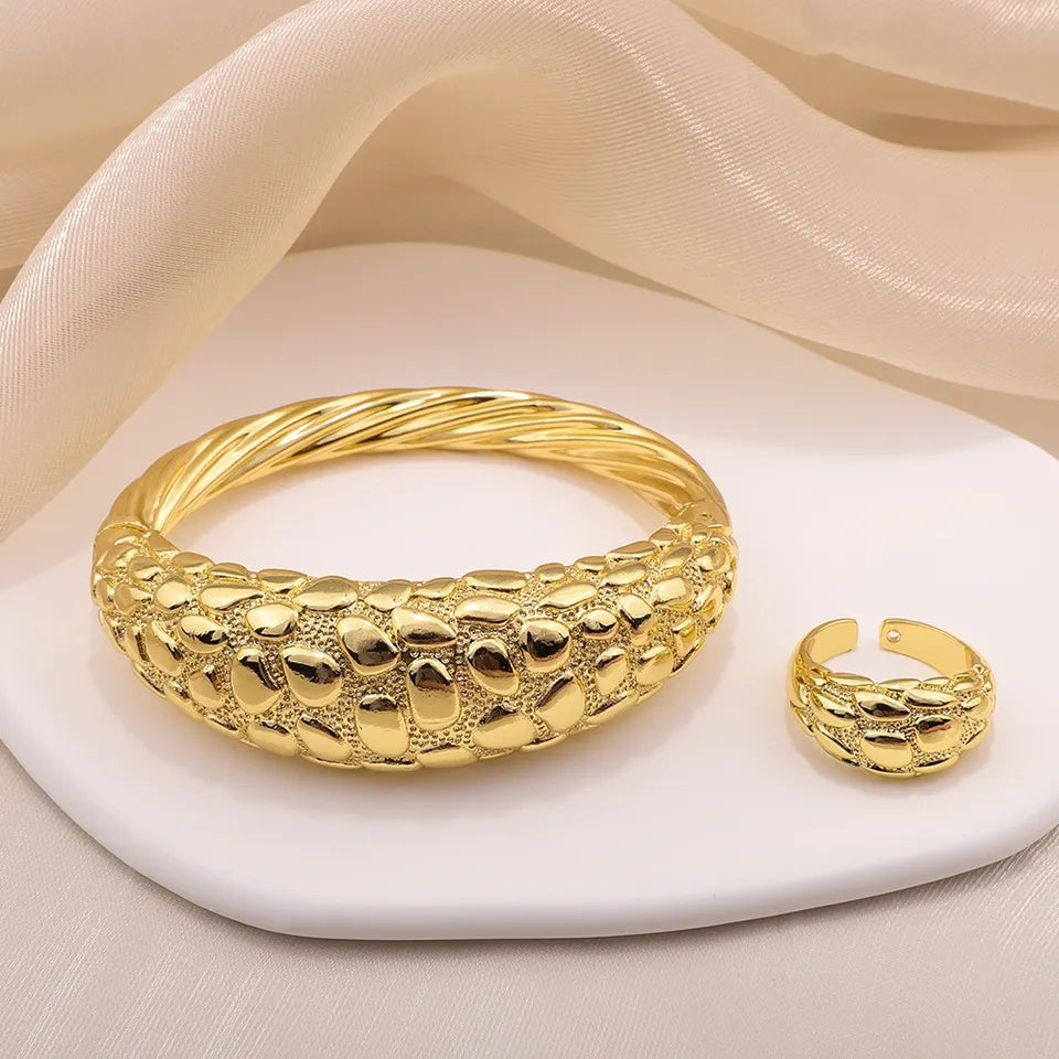 Gold bracelet and ring on a white stone with beige fabric background