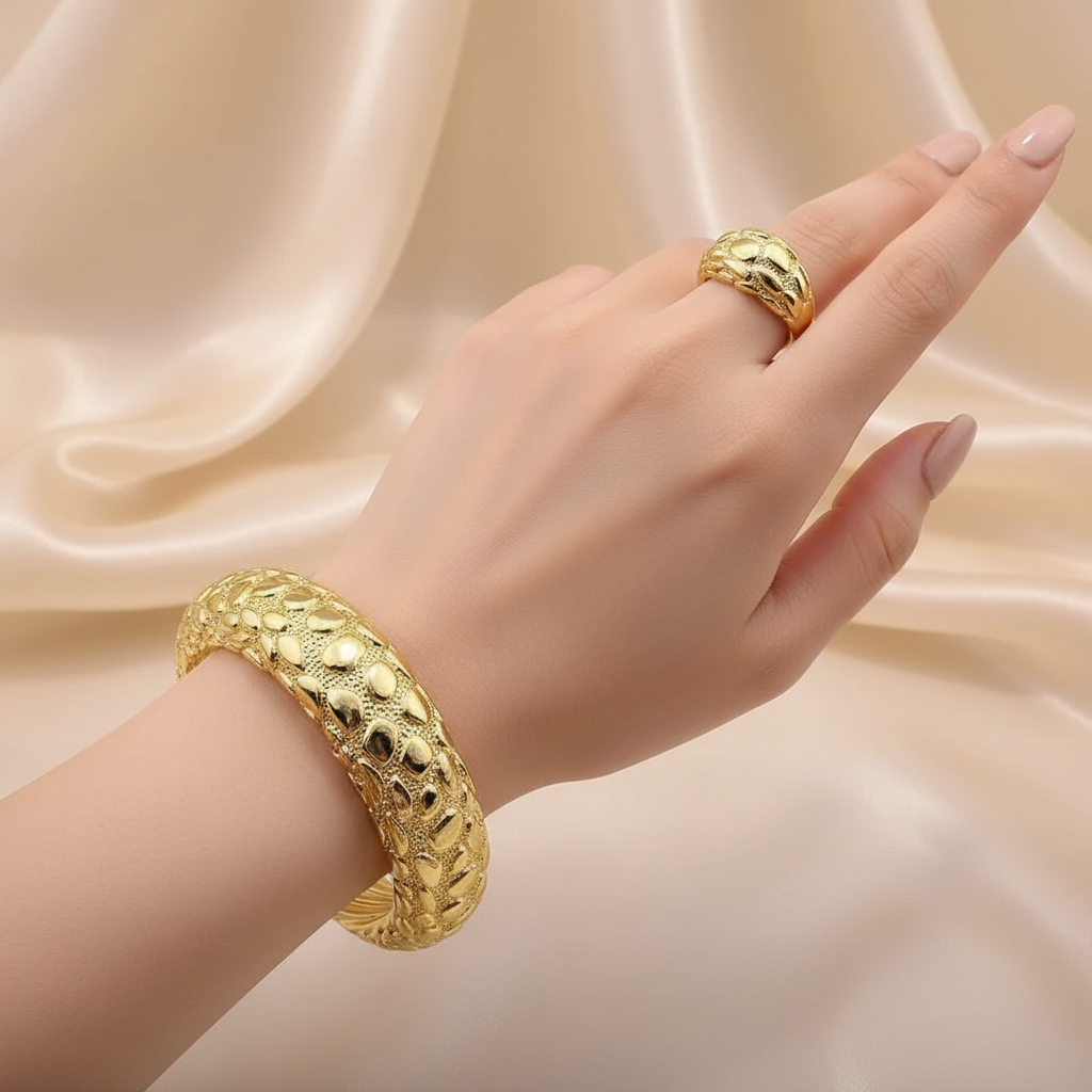 Gold bracelet and ring on a white stone with beige fabric background