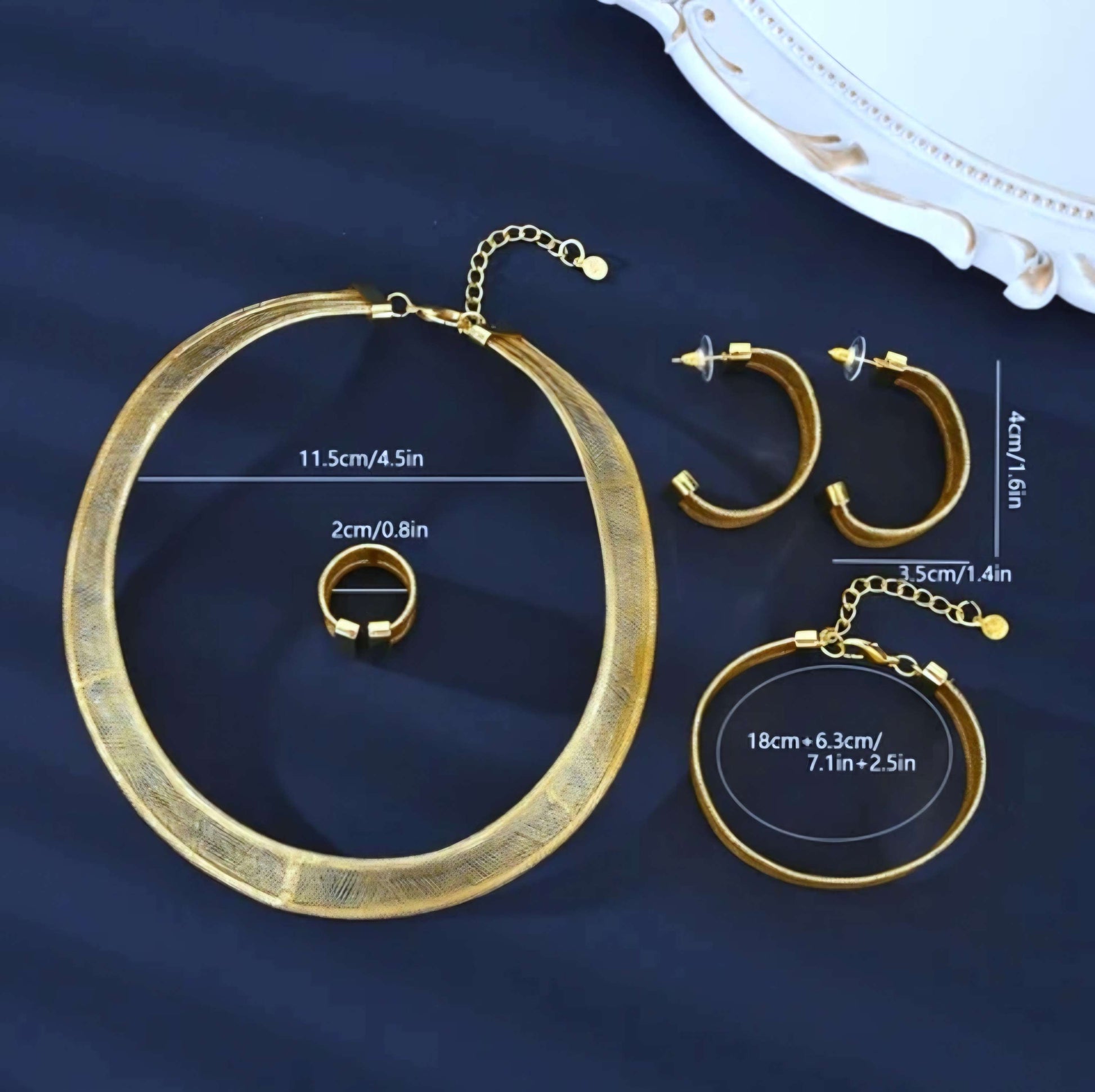 Gold jewelry set including necklace, ring, and earrings on a dark blue background with measurements.