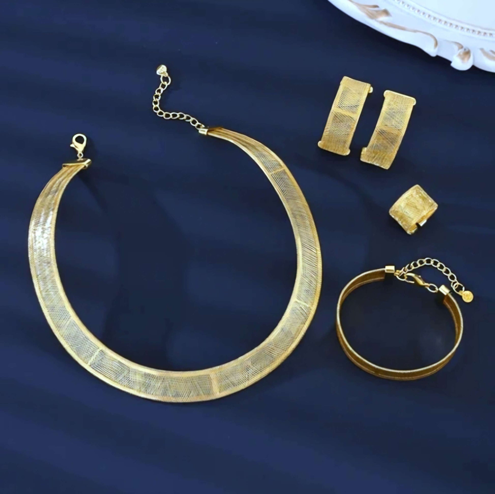 Gold necklace, bracelet, and earrings on a blue background