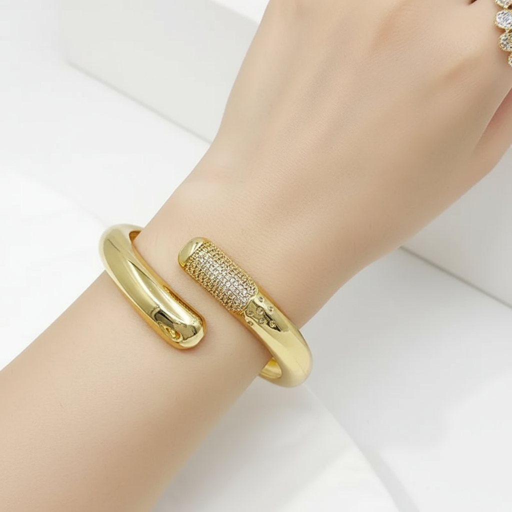 Gold bangles on a wrist against a white background