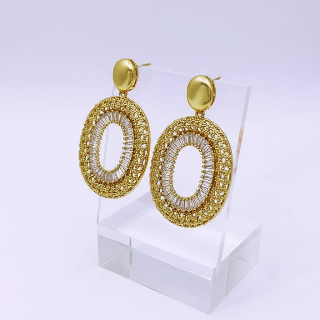 Gold earrings on a clear stand with a white background