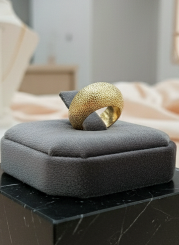 Gold ring on a gray cushion with a blurred background