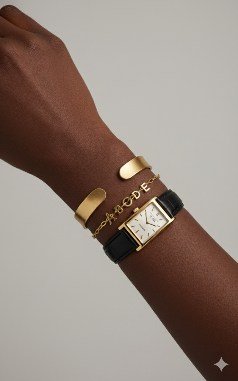Gold and brown bracelet with a watch on a wrist against a neutral background