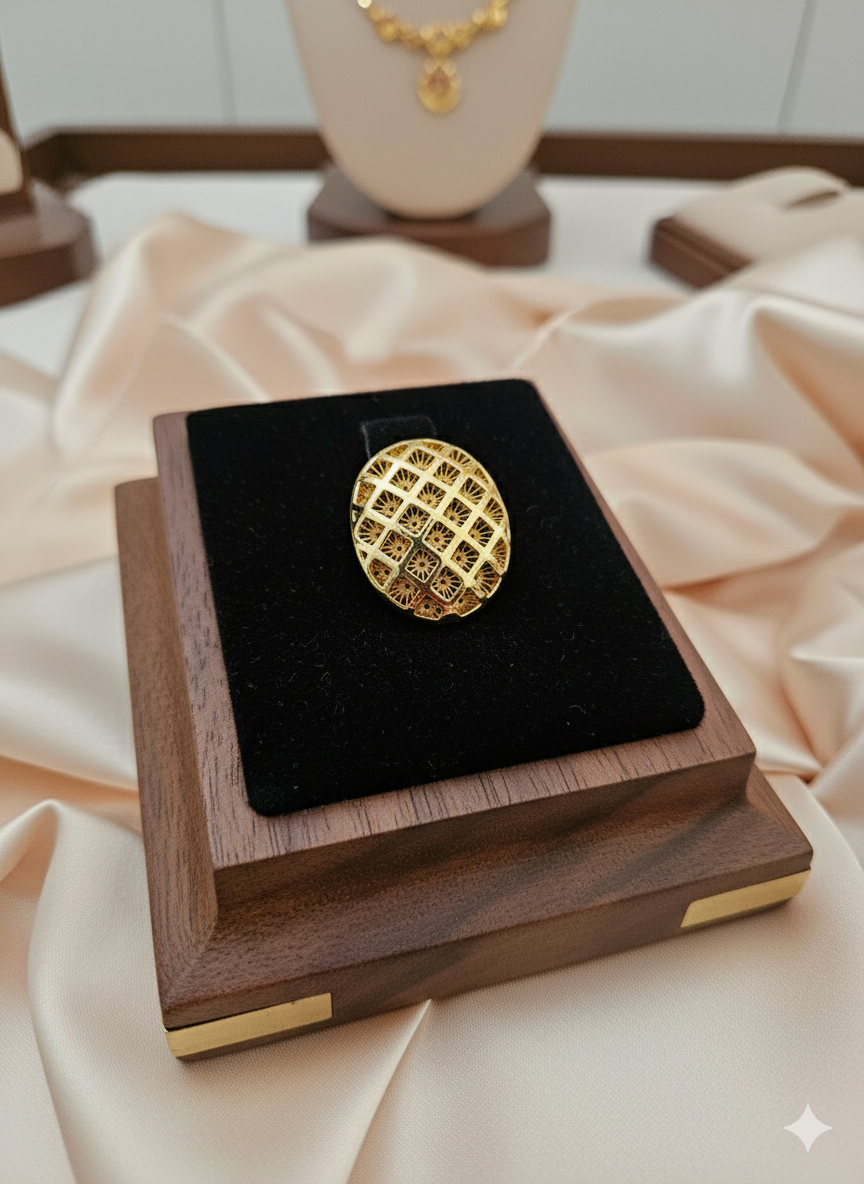 Gold ring on a black cushion inside a wooden box with a blurred jewelry display in the background.