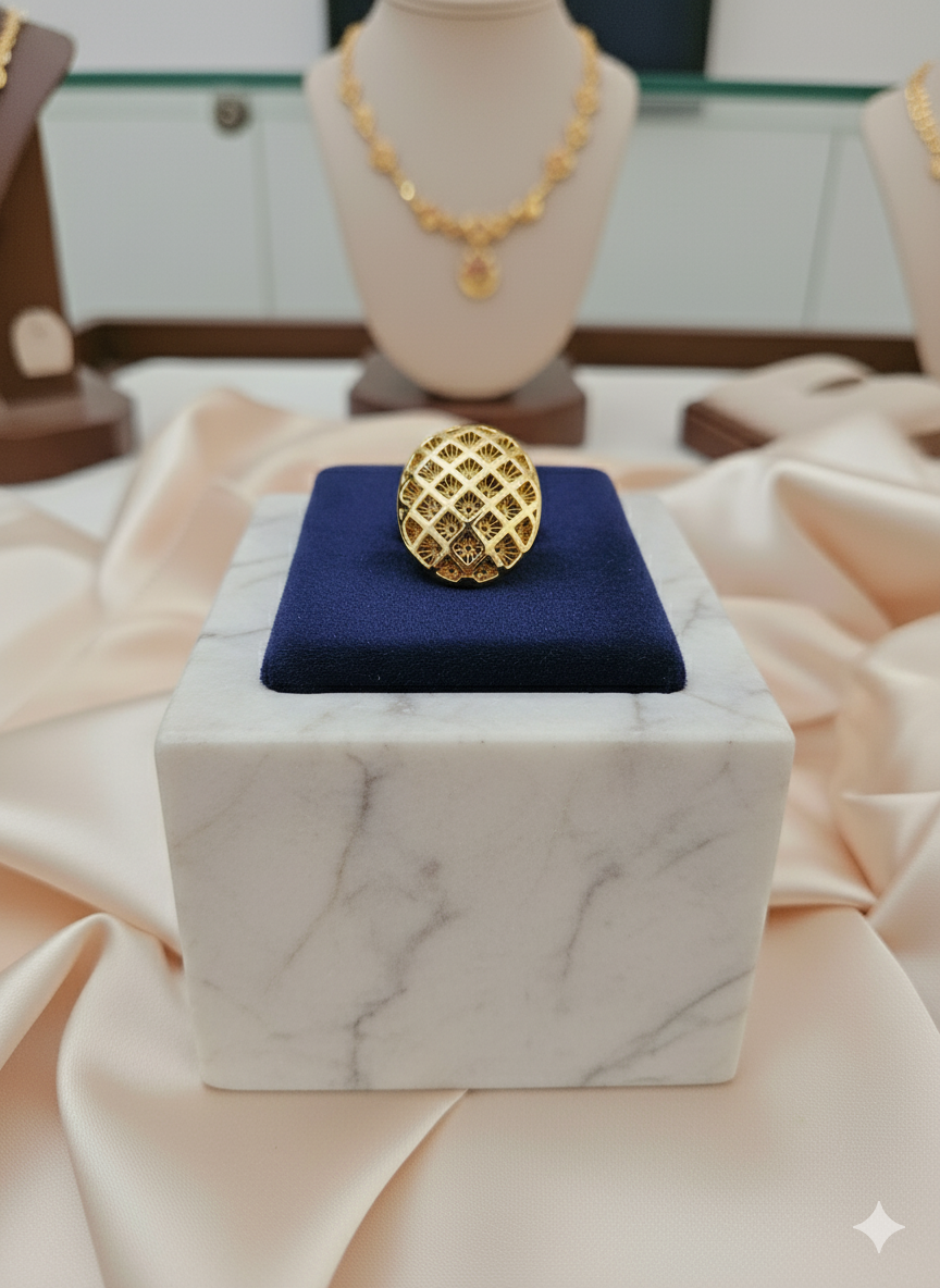 Gold ring on a blue cushion with a marble base, surrounded by other jewelry in the background.