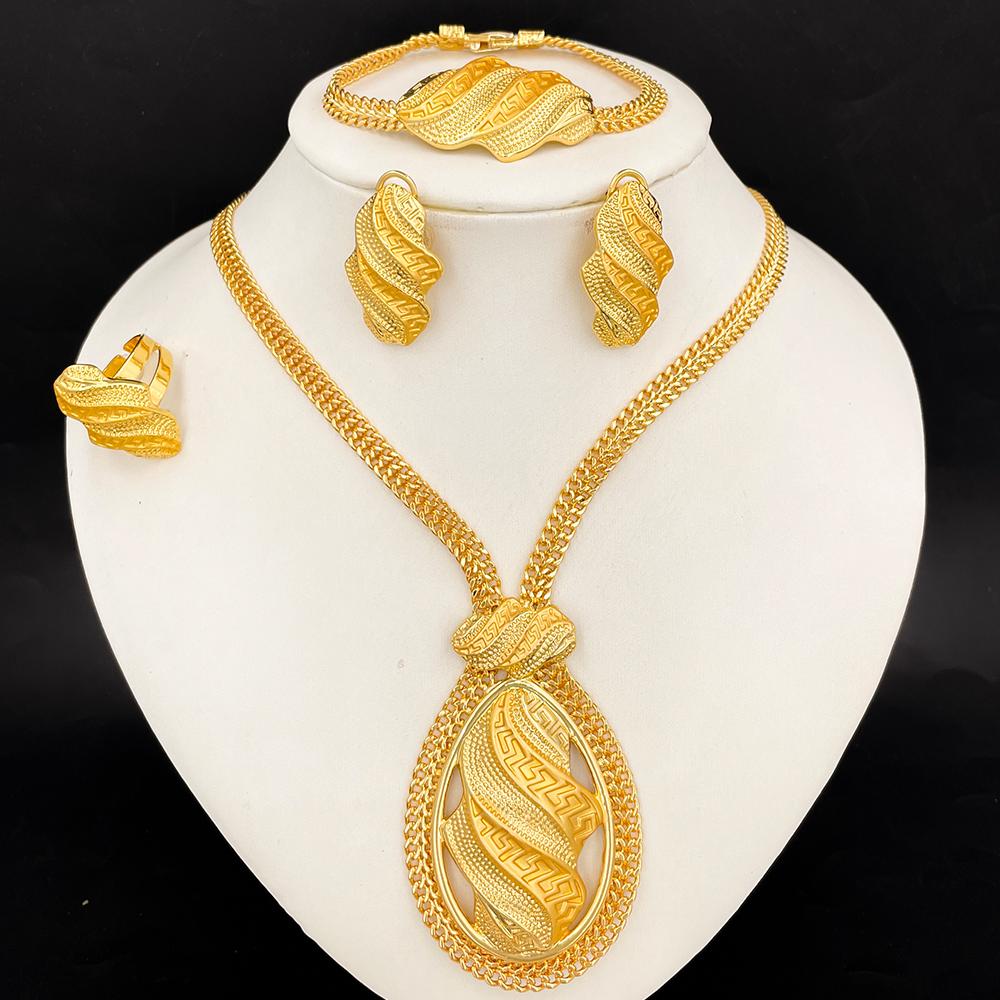 Gold jewelry set including necklace, earrings, and bracelet on a white stand with a black background.