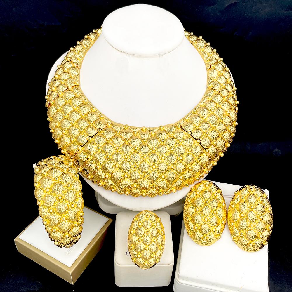 Gold necklace and earrings set on a white stand against a dark background