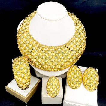 Gold necklace and earrings set on a white stand against a dark background