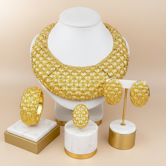 Gold jewelry set including necklace, earrings, and bangles on a beige background