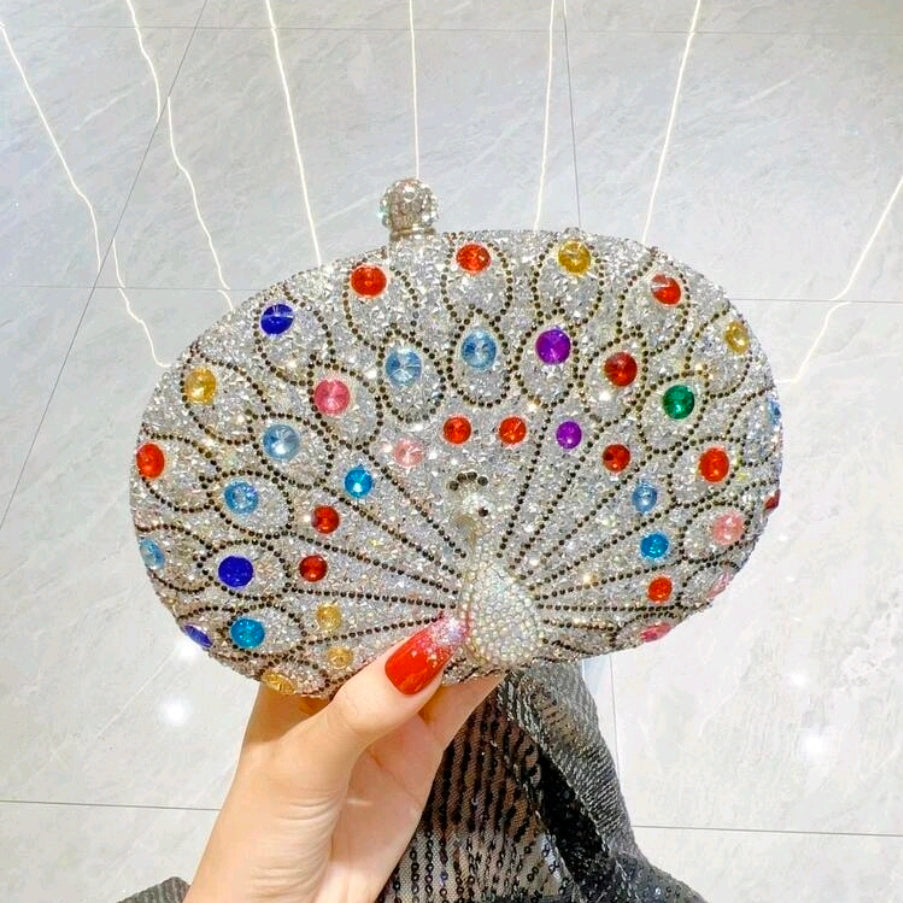 Decorative clutch bag with multicolored gemstones held by a hand against a neutral background