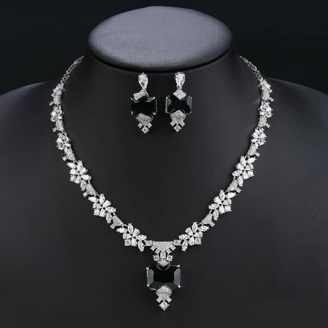 Jewelry set with necklace and earrings on a black mannequin against a dark background