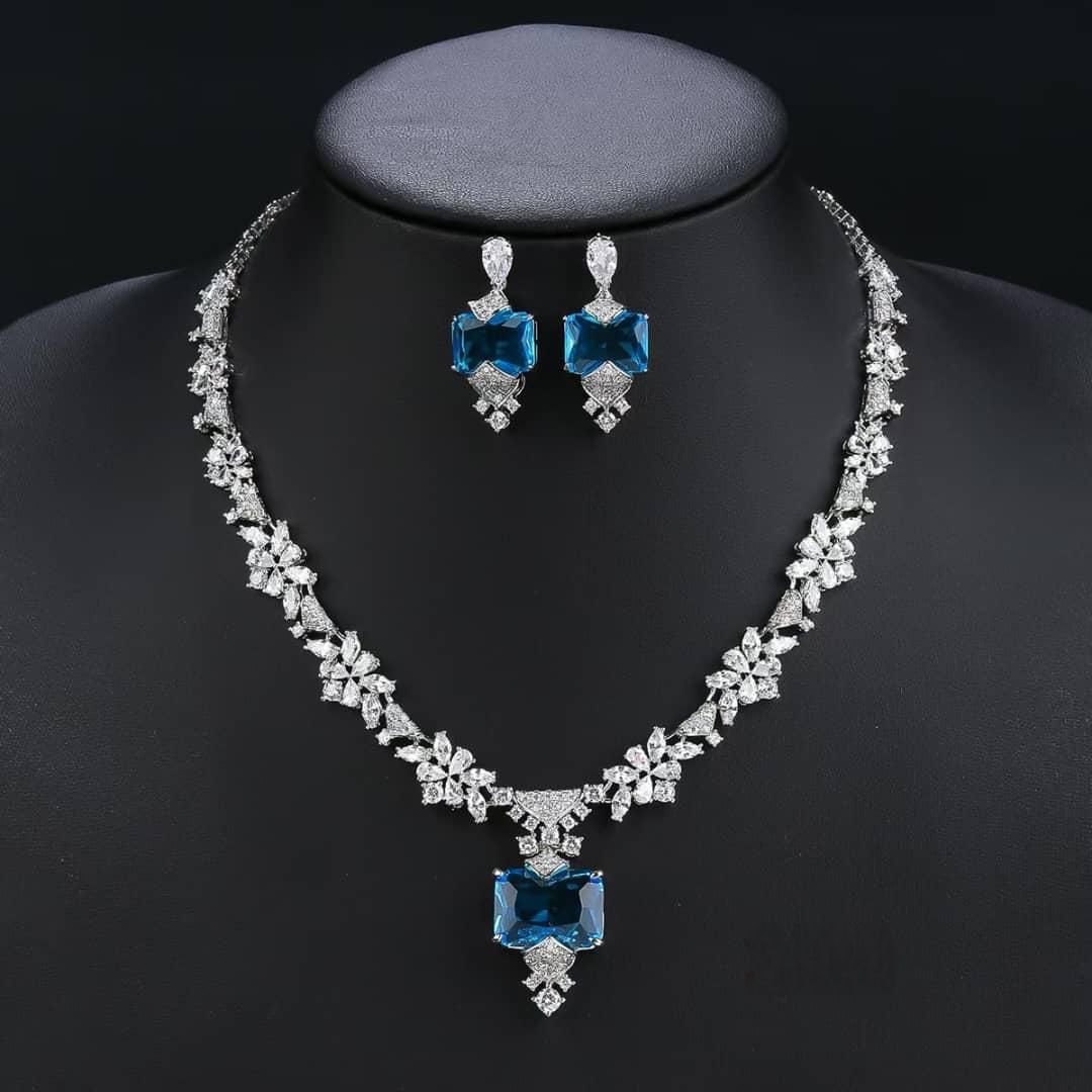 Jewelry set with necklace and earrings featuring blue gemstones on a black background