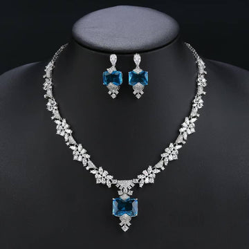 Jewelry set with necklace and earrings featuring blue gemstones on a black background