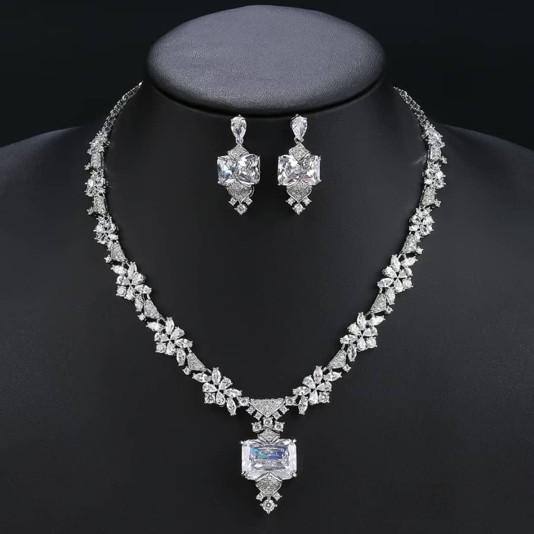 Diamond necklace and earrings set on a black mannequin with a dark background