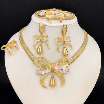 Gold jewelry set with necklace, earrings, and bracelet on a white stand against a black background