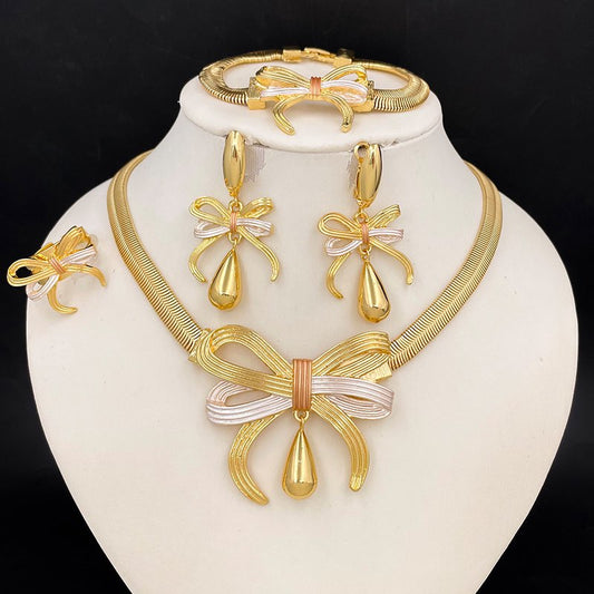 Gold jewelry set with necklace, earrings, and bracelet on a white stand against a black background