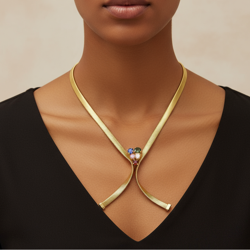 Woman wearing a gold necklace with a central gemstone on a neutral background