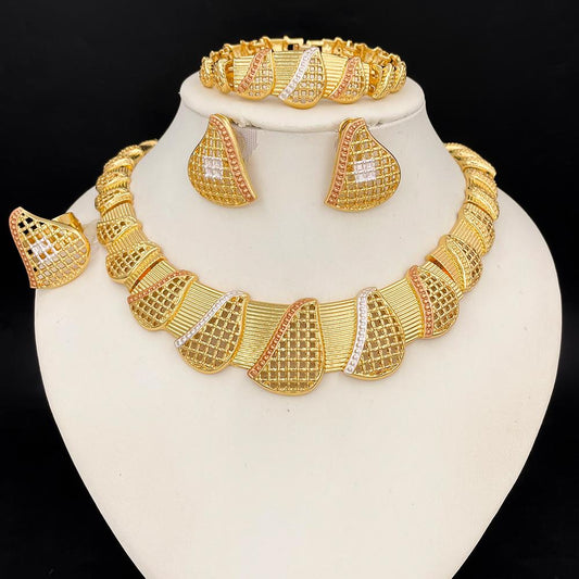 Gold jewelry set including necklace, earrings, and bracelet on a white stand with black background