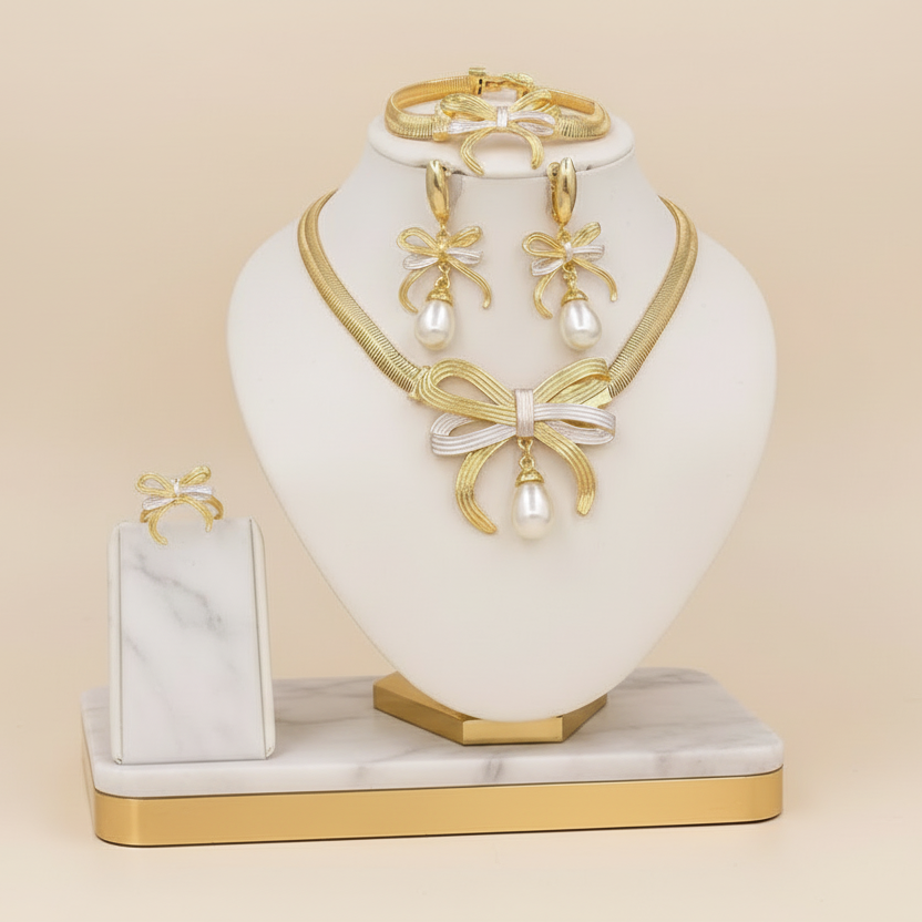 Jewelry set including a necklace, earrings, and bracelet on a white and gold stand against a beige background.