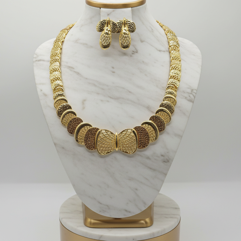 Gold necklace and earrings on a marble bust against a white background