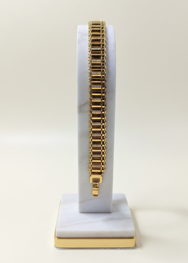 Gold bracelet on a white and gold stand against a white background