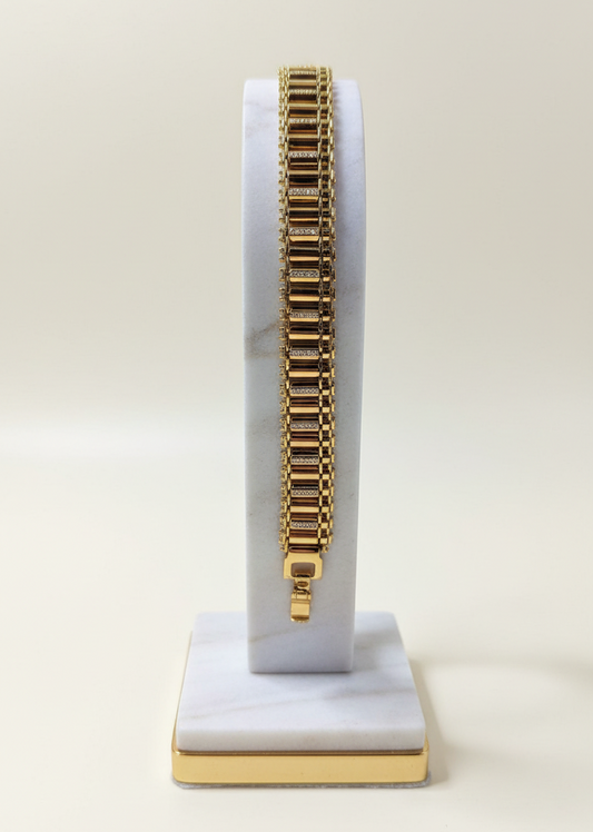 Gold bracelet on a white and gold stand against a white background