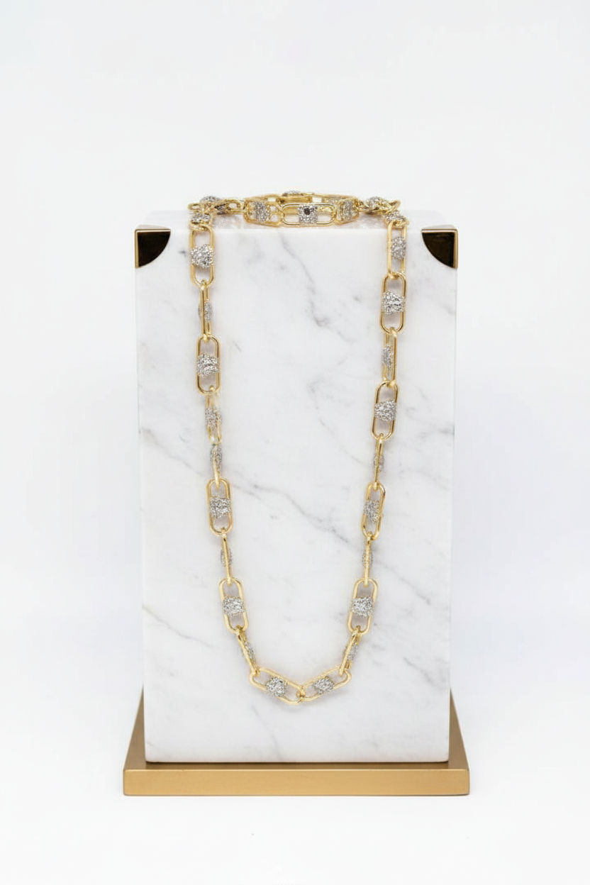 Gold and crystal necklace on a marble stand with gold base
