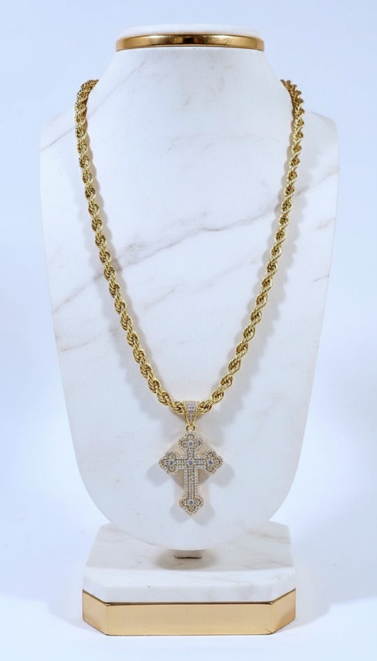 Gold chain necklace with a cross pendant on a white marble stand.