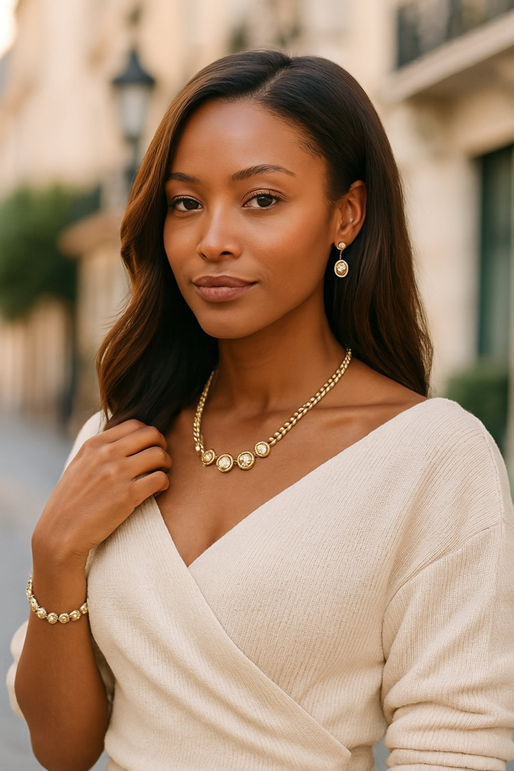 Woman wearing a beige sweater and gold jewelry outdoors