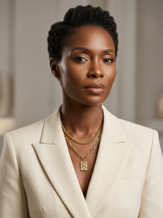 Woman wearing a beige blazer and gold necklace with a blurred background