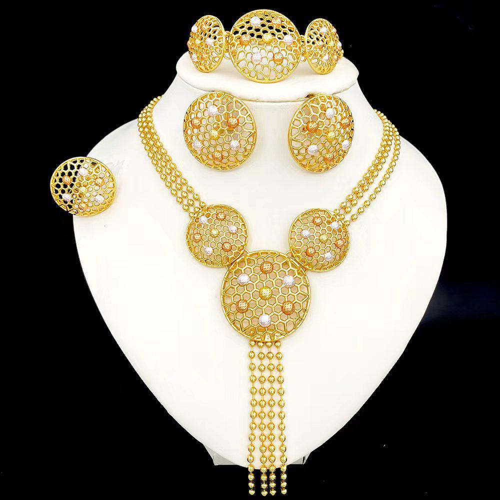 Gold jewelry set including necklace, earrings, and bracelet on a white stand.