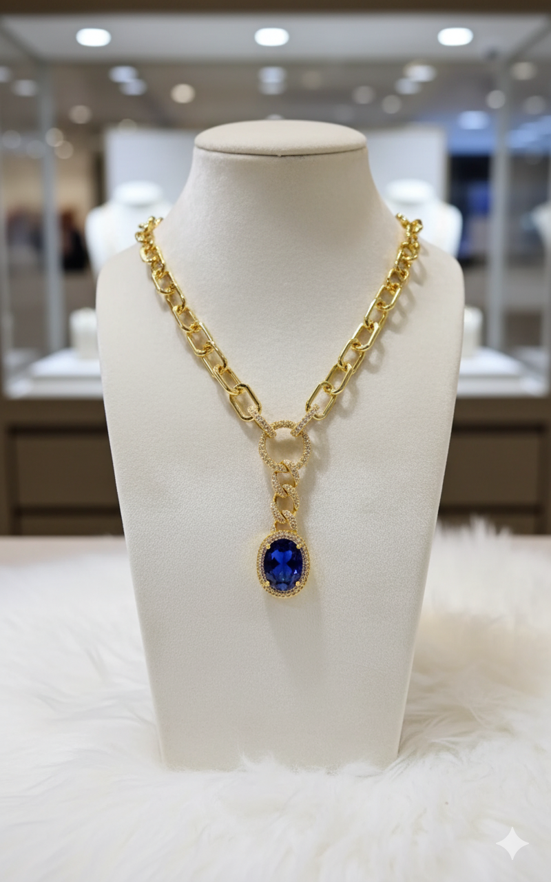 Gold necklace with a blue gemstone on a white mannequin bust in a store setting.