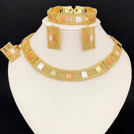 Gold jewelry set including necklace, earrings, and bracelet on a white stand with black background