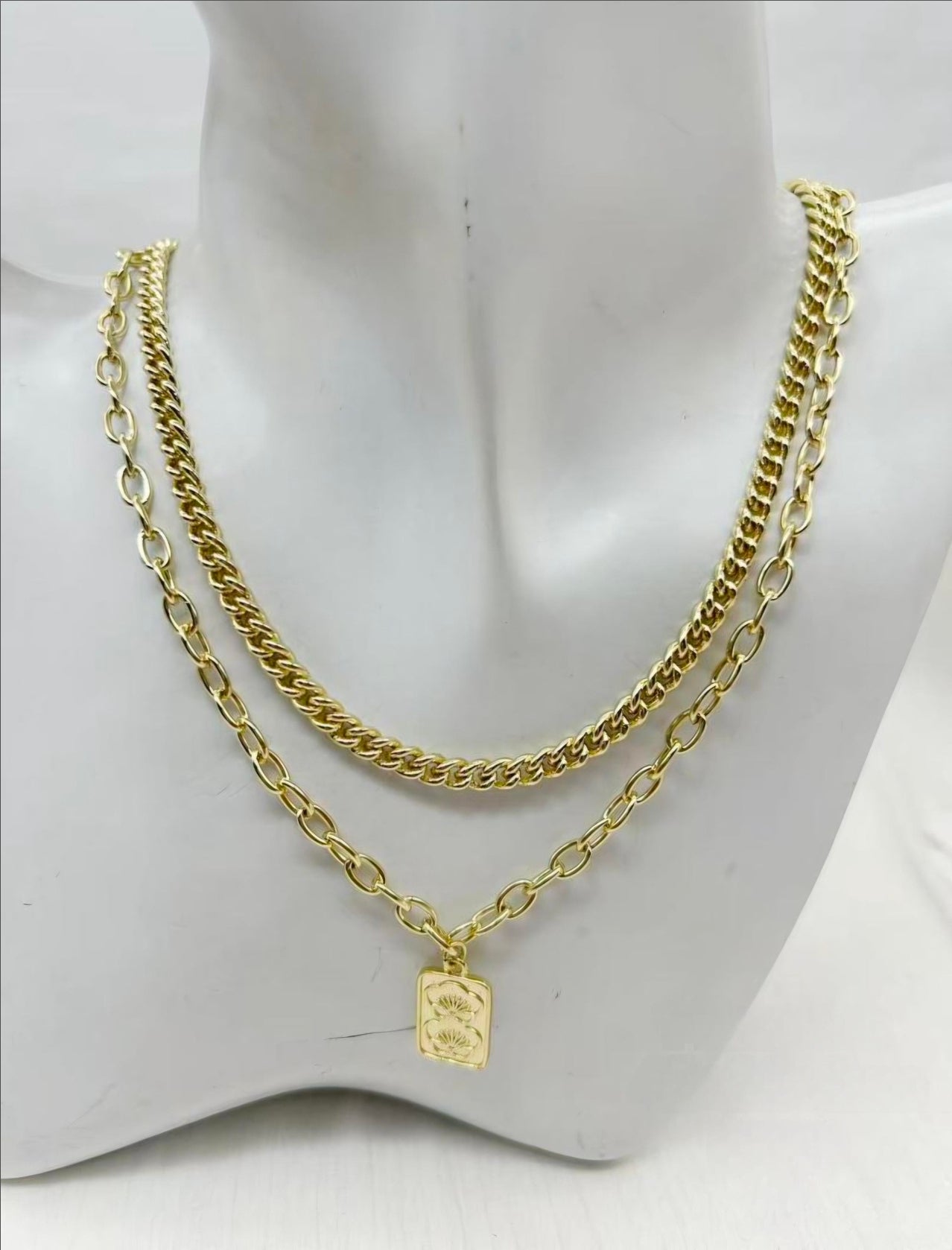 Gold chain necklace with a tag on a mannequin bust.