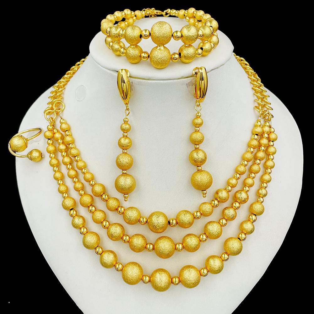 Gold jewelry set including necklace, bracelet, and earrings on a white stand.