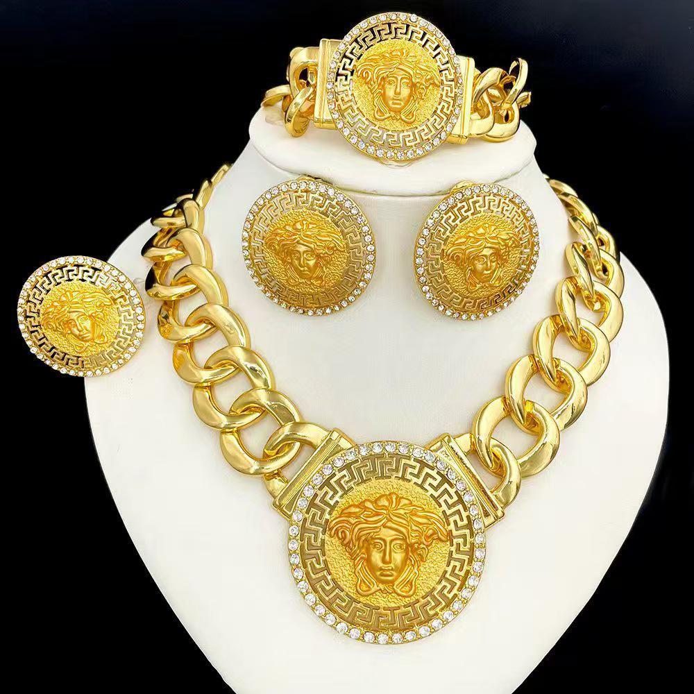 Gold jewelry set including necklace, earrings, and bracelet on a white stand with a black background.